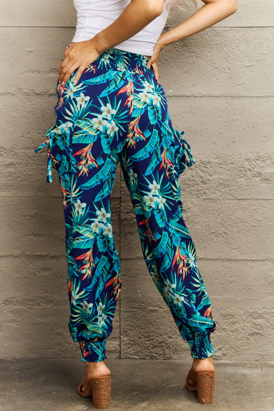Person wearing colorful tropical print pants against a gray wall.