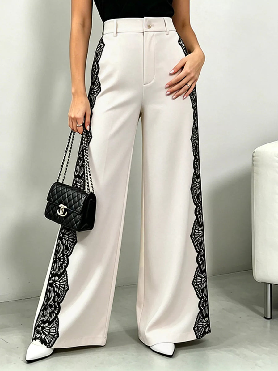 White pants with black lace trim worn by a person, holding a black handbag.