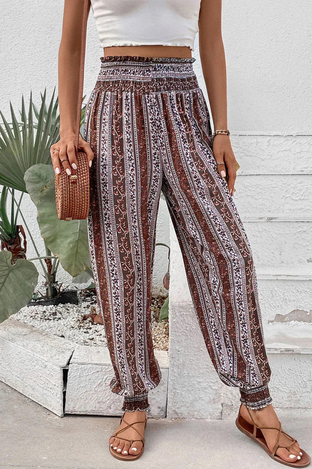Person wearing patterned pants and a white top in an outdoor setting.